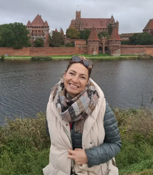 Kobieta pozująca do zdjęcia, w tle zabytek.