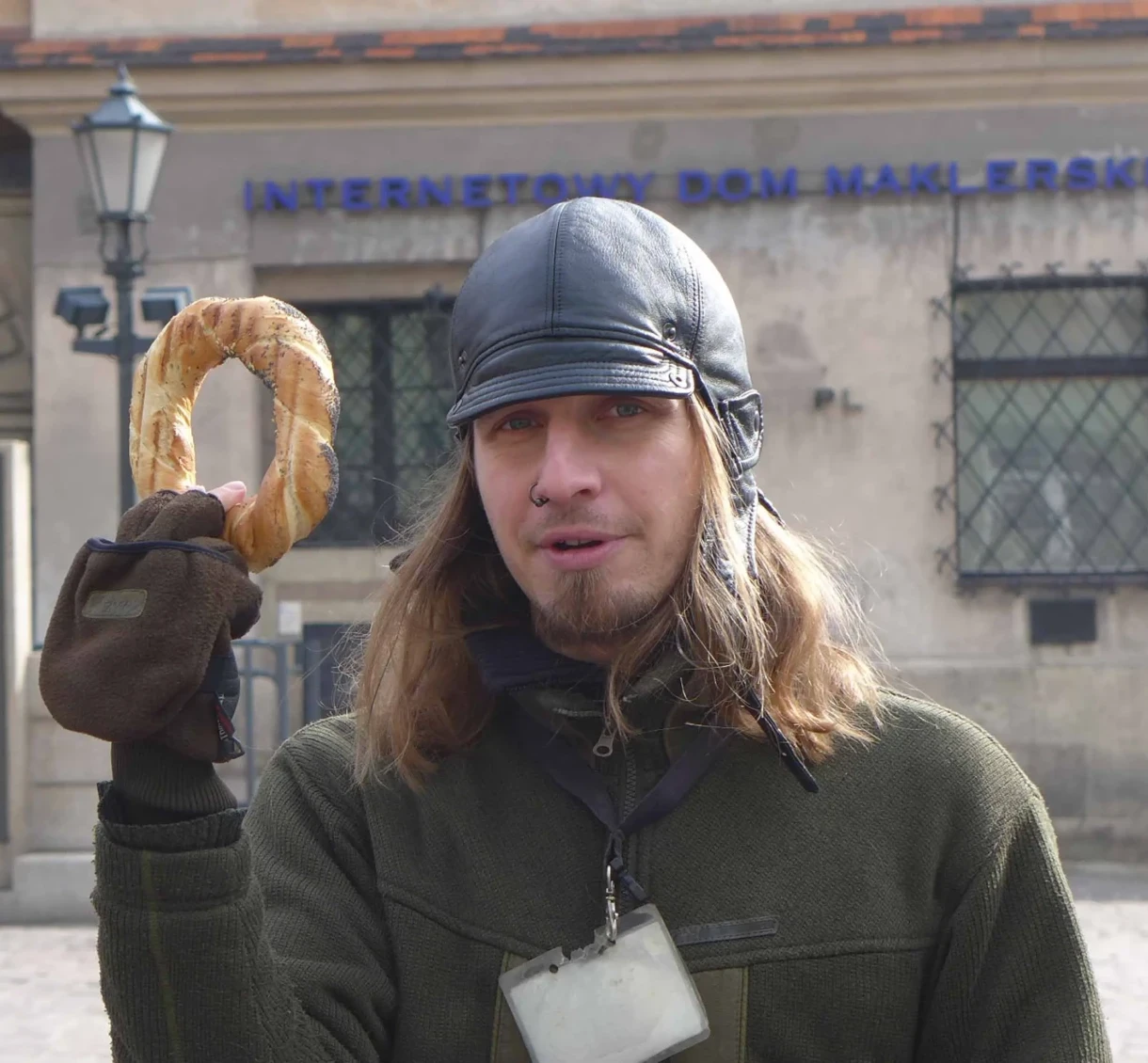 Mężczyzna trzymający obwarzanka w jednej ręce.