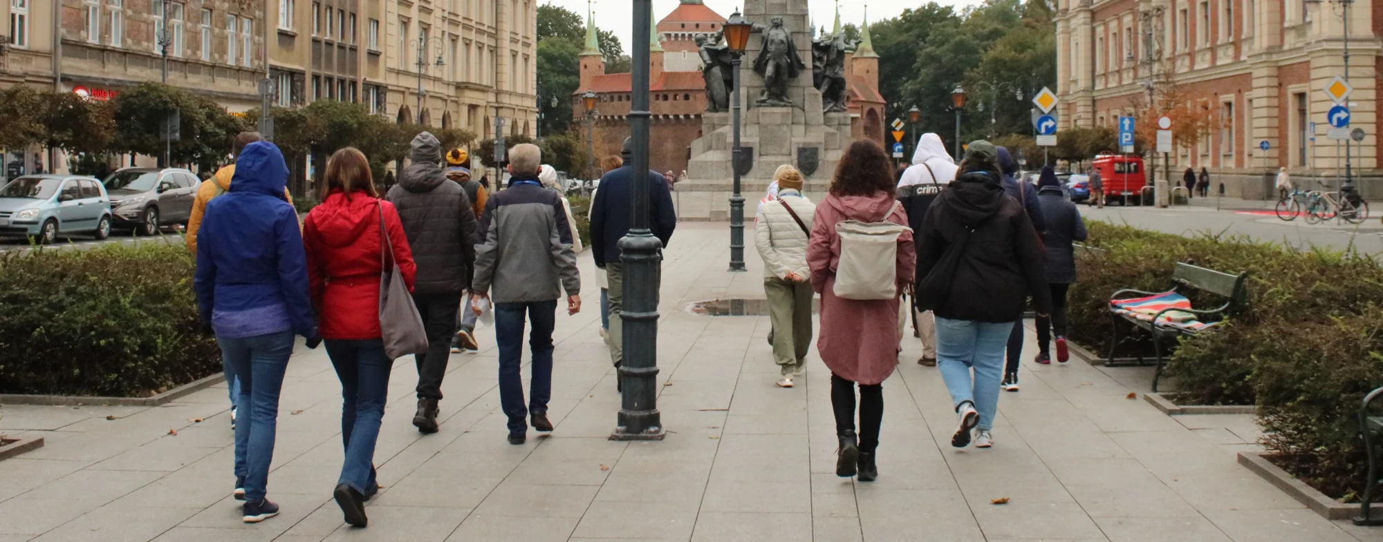 Grupa ludzi na Placu Matejki podąża w stronę Pomnika Bitwy pod Grunwaldem.