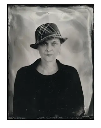 Czarno-białe zdjęcie kobiety w kapeluszu w kratę, stylizowane na retro.