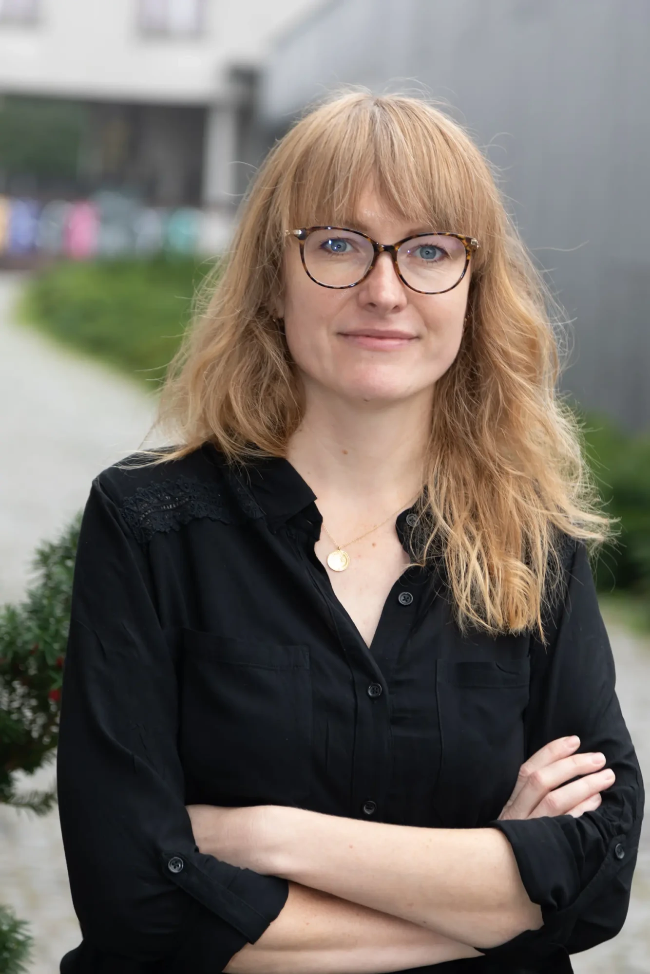 Blondwłosa kobieta z okularami uśmiecha się w stronę obiektywu.