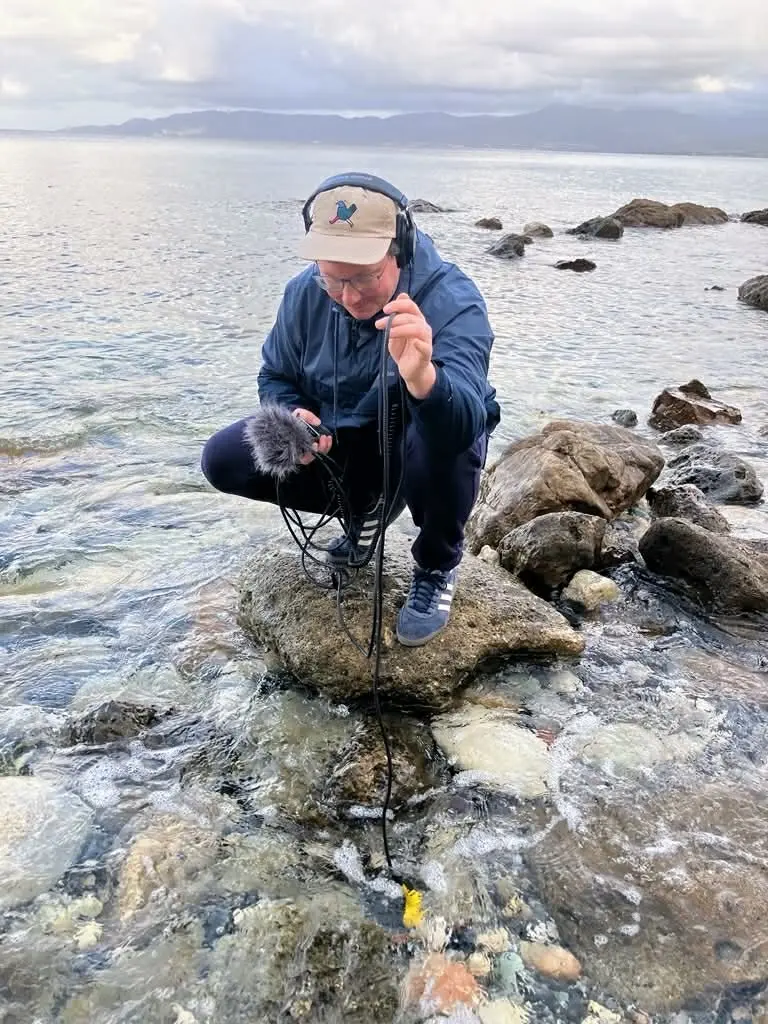 Mężczyzna trzymający specjalny mikrofon pod powierzchnią wody.